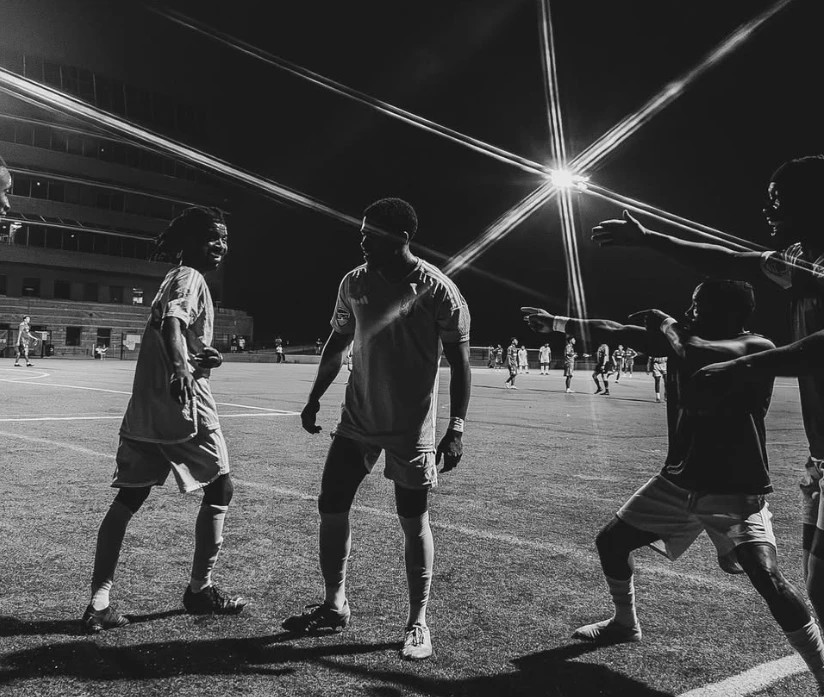 AUFC players celebrating together under the floodlights